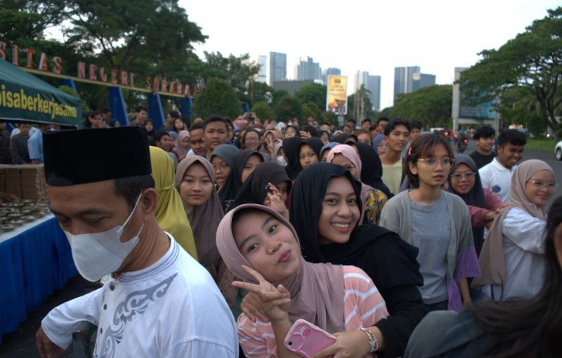 Students of Surabaya State University and local residents queue for takjil to break fast together in the front yard of the campus UNESA