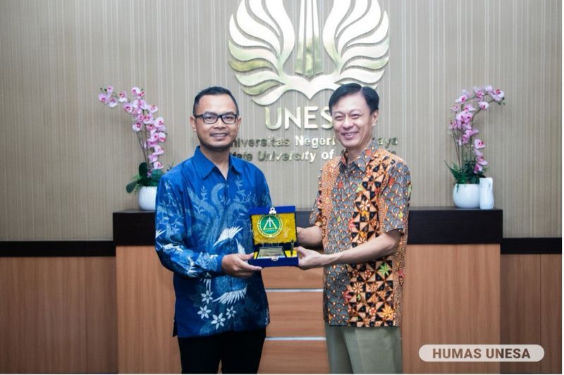 Direktur Unesa Global Engagement (UGE) Unesa, Muchamad Arif Al-Ardha (kiri), dan Direktur Eksekutif PPPK Petra, Hengkie Porawouw (kanan) bertukar cinderamata simbol kolaborasi.